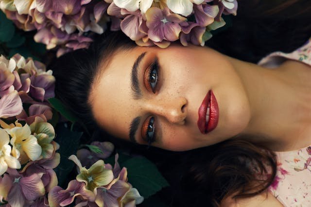 retrato de mujer rodeada de flores desde un ángulo inclinado